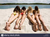 rear-view-of-pretty-girls-lying-on-sandy-beach-on-hot-summer-day-BWCFRM.jpg