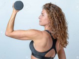 48720787-fit-middle-aged-woman-working-out-with-a-dumbbell-flexing-her-arm-to-strengthen-her-muscles